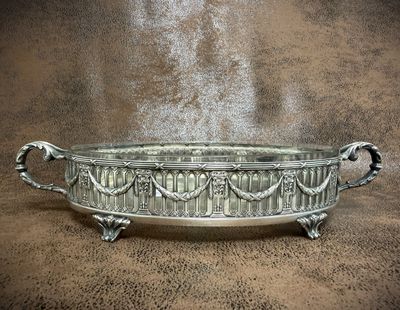 a large metal bowl with handles on a brown surface
