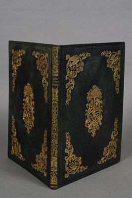 an old black and gold book sitting on top of a table