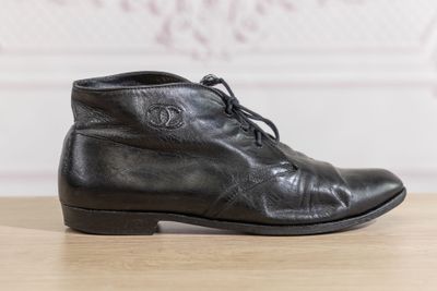 des bottines en cuir noir à lacets posées sur une table en bois