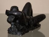 a black sculpture of a person laying on a glass table
