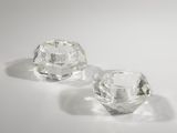 une paire de bougeoirs en verre transparent posés sur une surface blanche