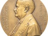 an image of a bronze medal with a man in a suit and bow tie
