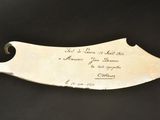 an old knife with writing on it sitting on a black surface
