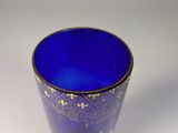 a blue glass with a gold design on it