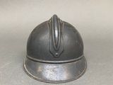 a small metal helmet on a table with a gray background