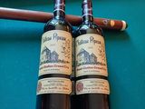 deux bouteilles de vin et un cigare posés sur une table de billard