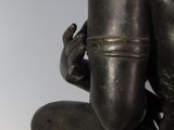 bronze statue of a kneeling man holding a bird in his right hand