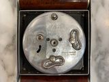 a silver clock in a metal box on a marble surface