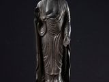 a bronze statue of a person standing on a black surface
