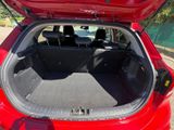 the back of a red car with its trunk open and the seats down
