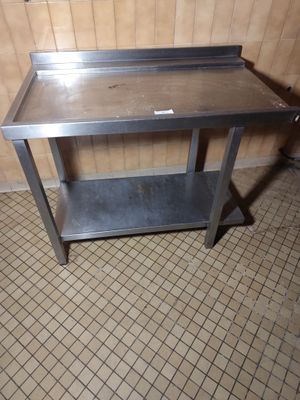 une table en métal avec une étagère posée dessus, dans une pièce