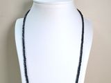 collier de perles noires sur un mannequin blanc portant une perle noire