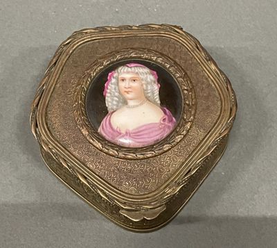 une boîte dorée sur laquelle figure l'image d'une femme en robe rose