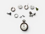 many different types of earrings and a watch on the table