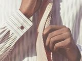 a man that is tying a tie on his shirt