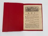 un livre ouvert à couverture rouge posé sur une table blanche