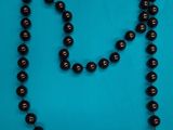 a close up of a black beaded necklace on a blue background