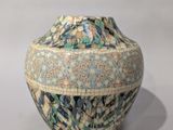 a blue and green vase sitting on a white surface