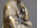 bronze statue of a man sitting on a stool with a drum