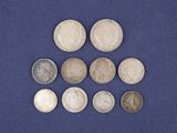 six types différents de pièces d'argent posées sur un tissu bleu
