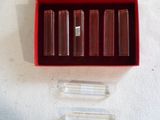 une boîte rouge contenant quatre rouges à lèvres, posée sur une surface blanche