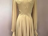 beige dress on a mannequin stand in front of a pink wall