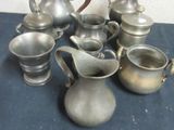 a lot of silver teapots and cups on a table