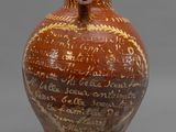 un vase marron portant une inscription, posé sur une surface grise