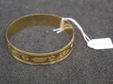 a close up of a gold bracelet with a tag on it