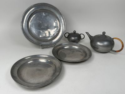 trois assiettes en argent et une théière en argent posées sur un plateau blanc