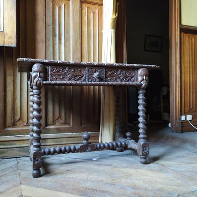 une table en bois au plateau sculpté, placée au milieu d'une pièce