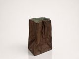 a brown paper bag with a handle sitting on a white surface