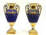 une paire de vases bleus et dorés posés sur une surface blanche