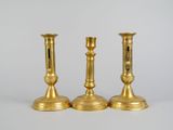 trois chandeliers en or posés les uns à côté des autres sur une table