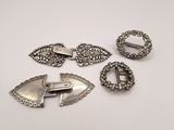 a group of silver metal brooches and buckles on a white surface