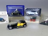 Quatre modèles réduits de voitures sont posés dans des boîtes en plastique sur une table.
