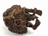 a small wooden sculpture of a frog on a white surface