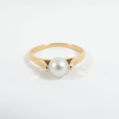 a gold ring with a white pearl in the center