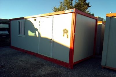 two portable buildings in a parking lot with a person standing in the doorway