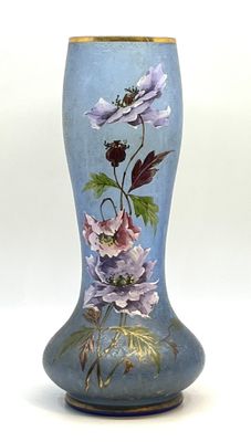 un vase bleu sur lequel sont peintes des fleurs sur fond blanc