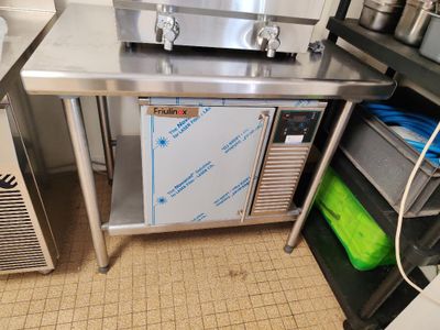 une cuisine équipée d'un plan de travail en inox et d'un réfrigérateur