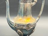 a silver tea pot with a yellow light inside of it