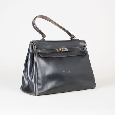 un sac à main en cuir noir muni d'une poignée en métal, sur fond blanc
