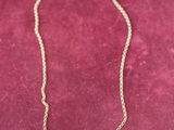 a gold necklace with a bar on it sitting on a red velvet surface