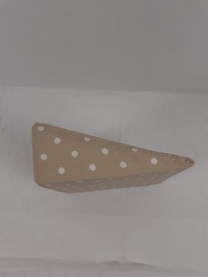 Ce coussin décoratif beige paré de pois blancs possède des o…