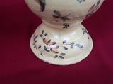 a white vase with a bird design on it on a table