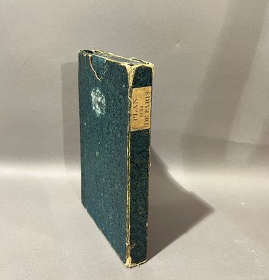 un vieux livre posé sur une table blanche à côté d'un mur blanc