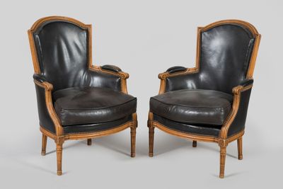pair of black leather armchairs with carved wood arms