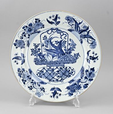 une assiette bleue et blanche sur laquelle est représenté un oiseau en cage