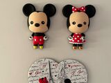 figurines de Mickey et Minnie Mouse posées sur un fond blanc orné d'un cœur